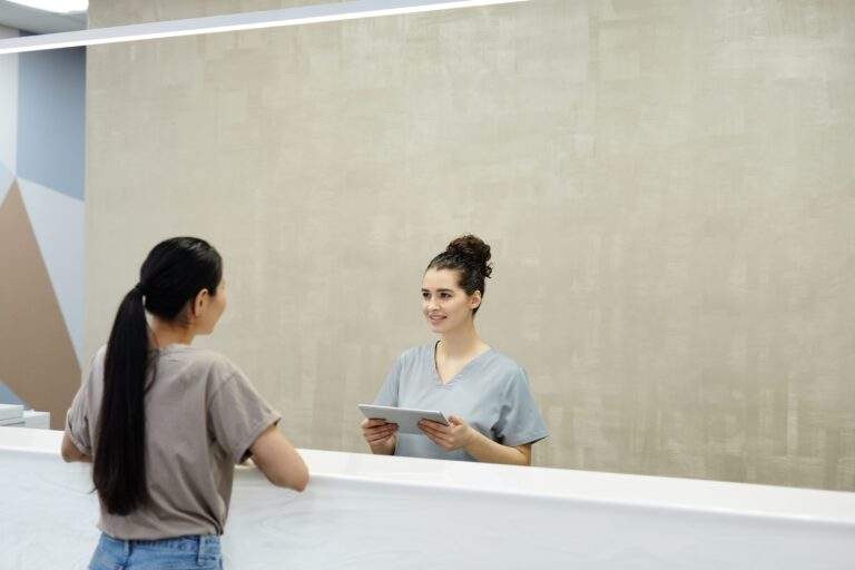 Medical receptionist assisting a patient at a clinic reception desk