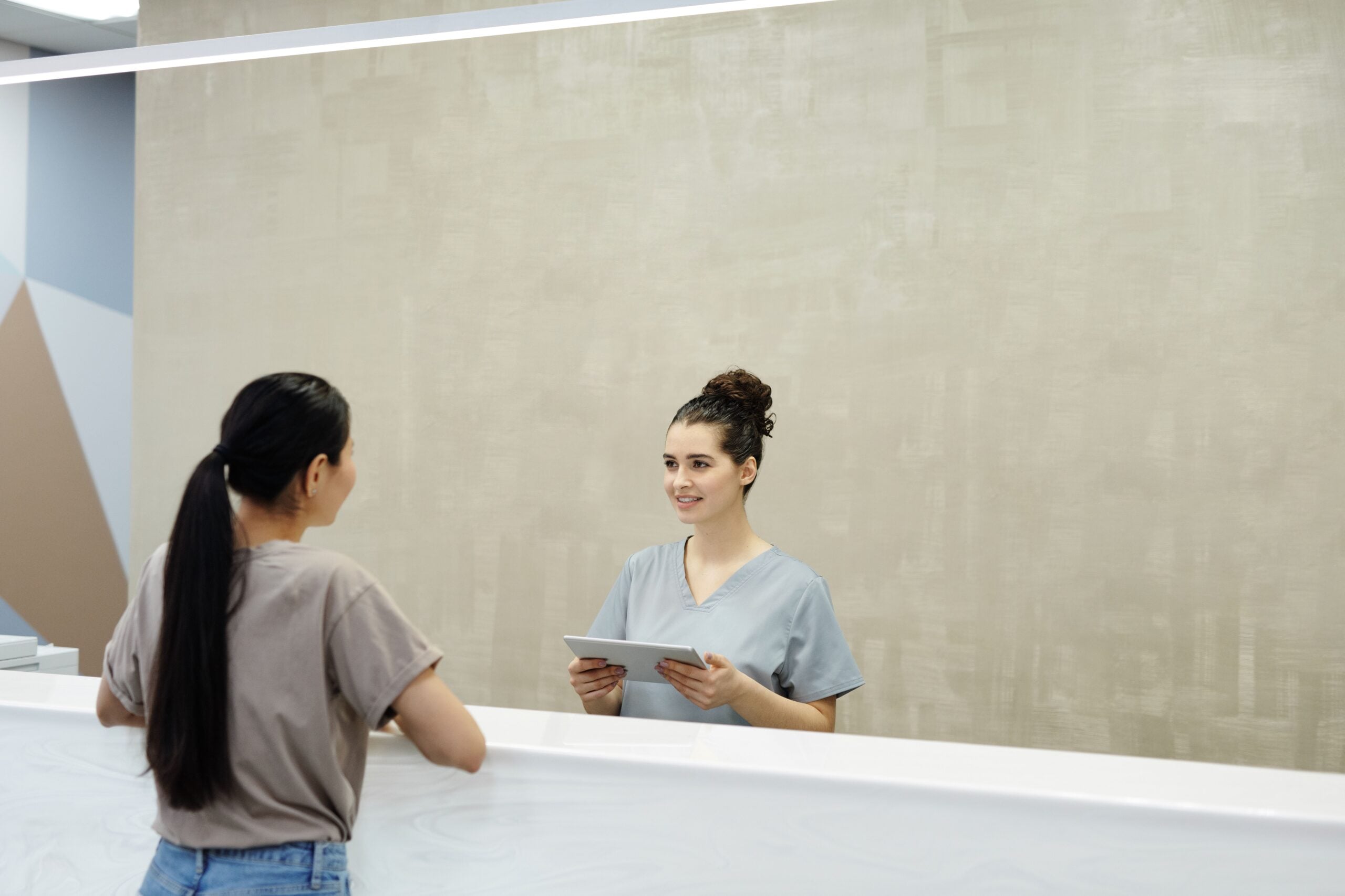 Medical receptionist assisting a patient at a clinic reception desk