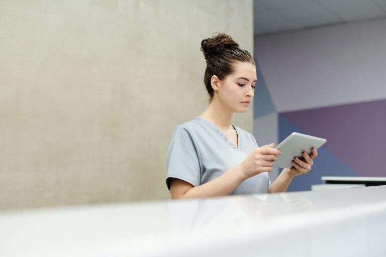 Medical receptionist using a tablet at a clinic reception desk