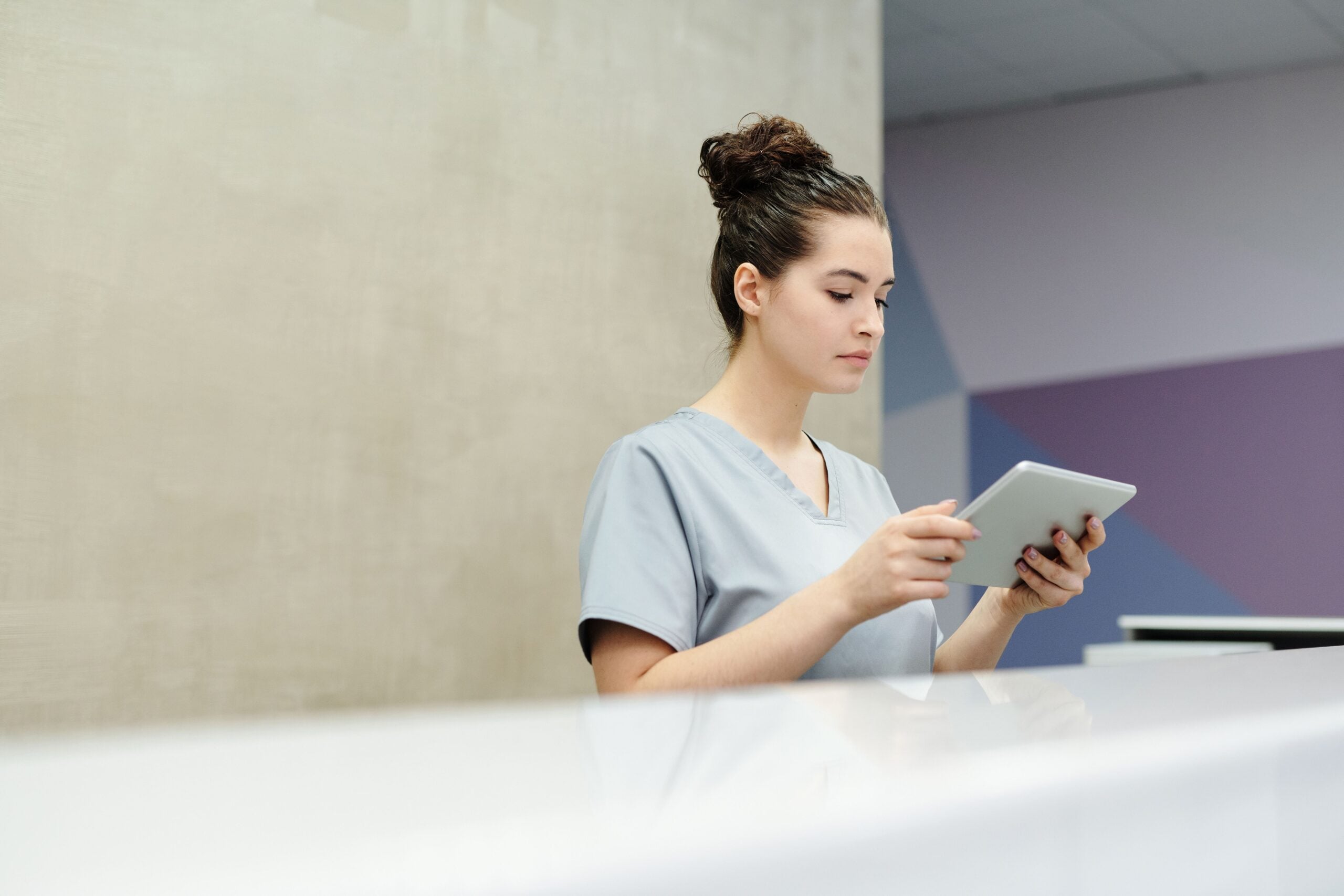 Medical receptionist using a tablet at a clinic reception desk